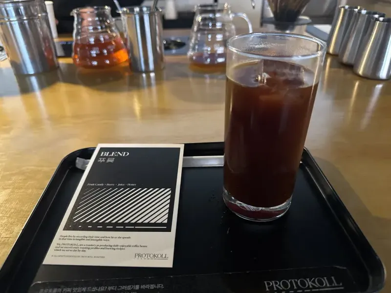 테이블 램프 아래 놓인 아이스 아메리카노와 레몬 케이크