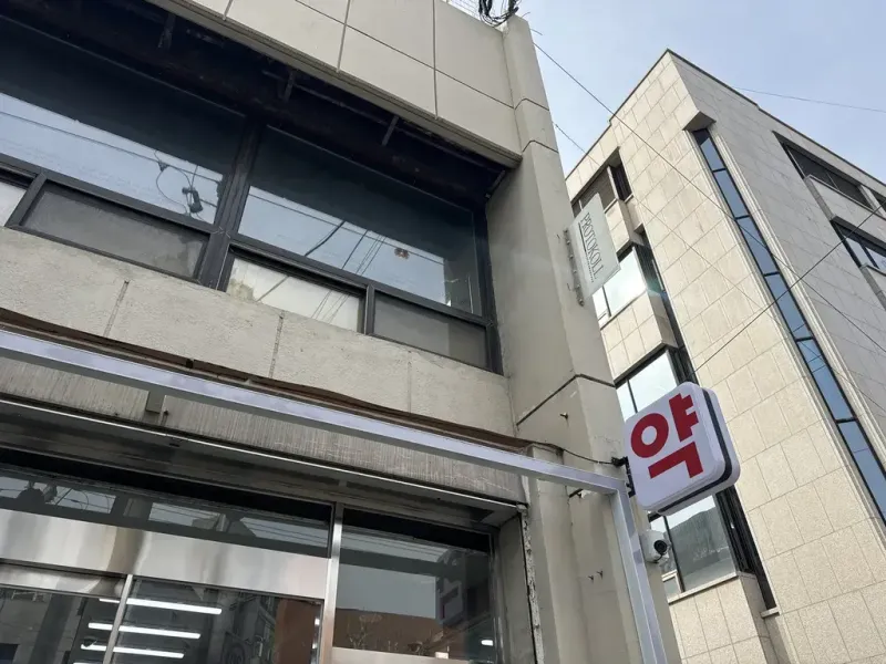 건물 벽면에 부착된 작고 미니멀한 프로토콜 영문 간판 클로즈업